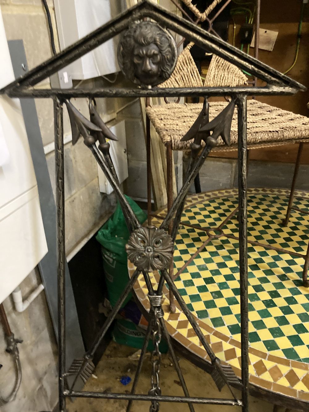 An iron framed circular tiled top table, a set of six iron framed chairs, with rope work seats and a wrought iron easel, table 128 diam